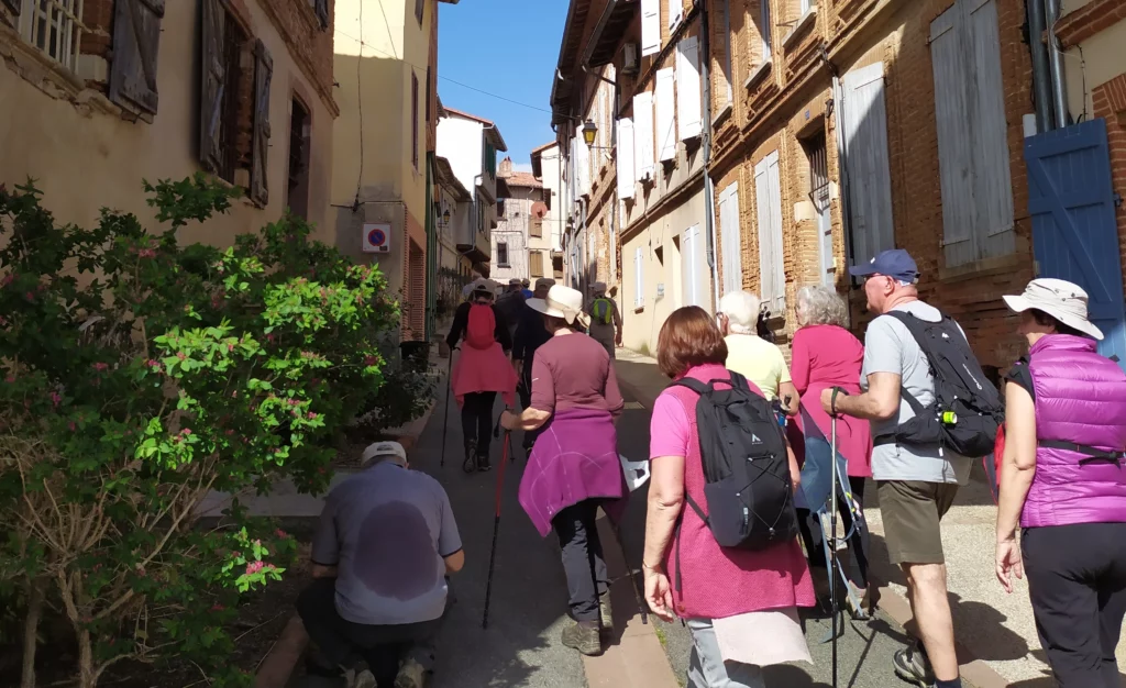 Randonneurs déambulant dans une rue du vieux Verfeil