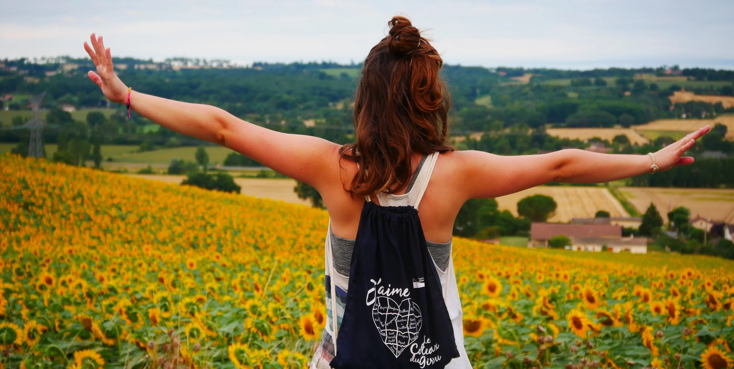 Image promotionnelle - Une femme de dos regardant le paysage des coteaux du Girou